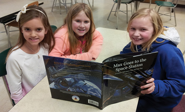 The Story Time from Space project includes videotapes of astronauts reading selected stories from the cupola of the ISS and conducting simple physics demonstrations that complement ST EM concepts in the book. Students follow along with <i>Max Goes to the Space Station</i>, written by Dr. Jeff Bennett and NASA Astronaut Alvin Drew. (Photo courtesy of CASIS.)
