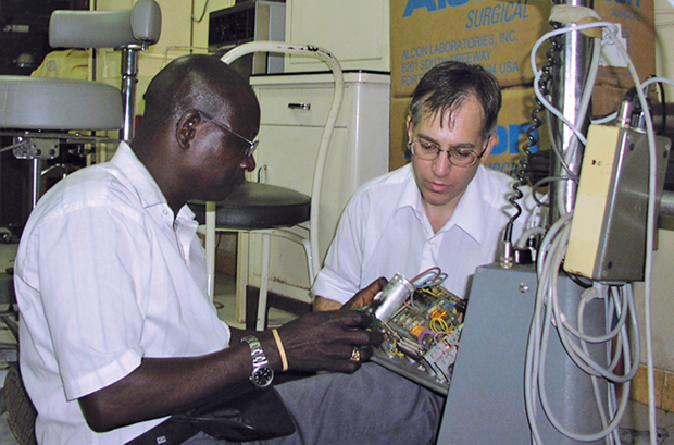FIGURE 3: Malkin (right) assists in the repair of a microscope in Sierra Leone. (Photo courtesy of Duke University.)