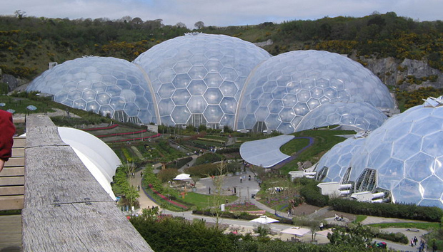 The Eden Project, designed by architect Nicholas Grimshaw in Cornwall, England. The complex is dominated by two huge enclosures consisting of adjoining domes that house thousands of plant species. Each enclosure emulates a natural biome. The first dome emulates a tropical environment, and the second a Mediterranean environment.