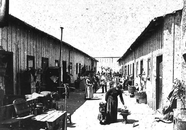 This photo was taken in a Buenos Aires conventillo (in Spanish, diminutive of convent), most likely in the early 1900s. A long patio-like area bordered on both sides by two rows of several rooms was typical. Each room housed a complete family, often with several children, and sometimes including grandparents and perhaps other relatives, too. A woman is shown, perhaps cooking food (a puchero?) in a coal brazier. (Photo courtesy of http://diasdehistoria.com/ar.)