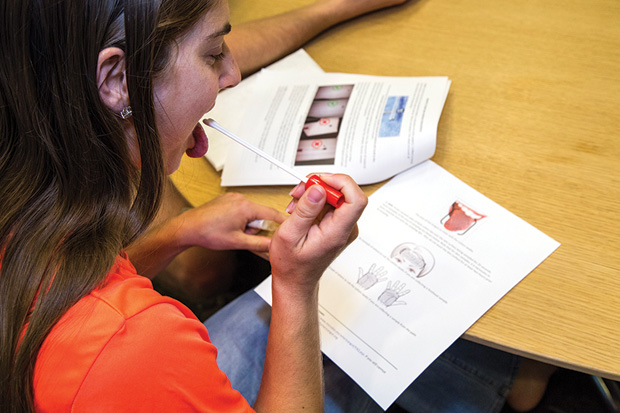 Figure 2: The American Gut Project encourages people to send in microbiome samples for analysis. Here, a participant follows the directions to swab her tongue, before sending in her sample. (Photo courtesy of the University of California, San Diego.)