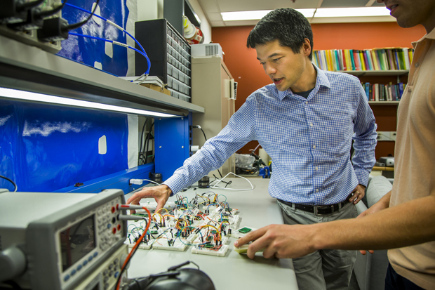 Dr. Fu examines a micro-electro-mechanical accelerometer sensor, common to many types of technology. His group has shown that a YouTube video containing music can be played on a particular smartphone and take control of its accelerometer. Photo by Joseph Xu, University of Michigan College of Engineering.