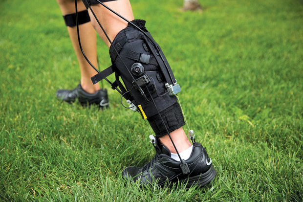 Figure 7: Bowden cables located adjacent to the ankle are retracted by an off-board actuation unit. Gyroscopes in the modified shoe, along with load cells in the calf wrap and leg strap, are used to detect gait events and measure the force being transmitted by the Bowden cables. These parameters are inputs for the exosuit’s control algorithm. (Image courtesy of Wyss Institute at Harvard University.)