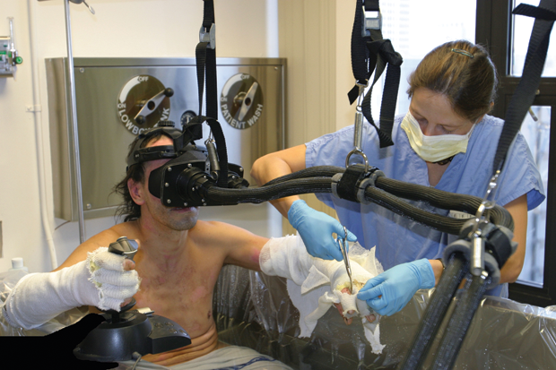 Figure 4. A special fiberoptic helmet allows a burn patient to use VR pain distraction during wound care, which occurs while sitting in a tub of water. With this helmet, only light—and no electricity—reaches the patient. (Copyrighted photograph by Hunter Hoffman/www.vrpain.com.)