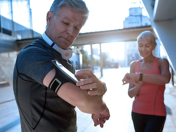 Male and female runners look at their smart watches